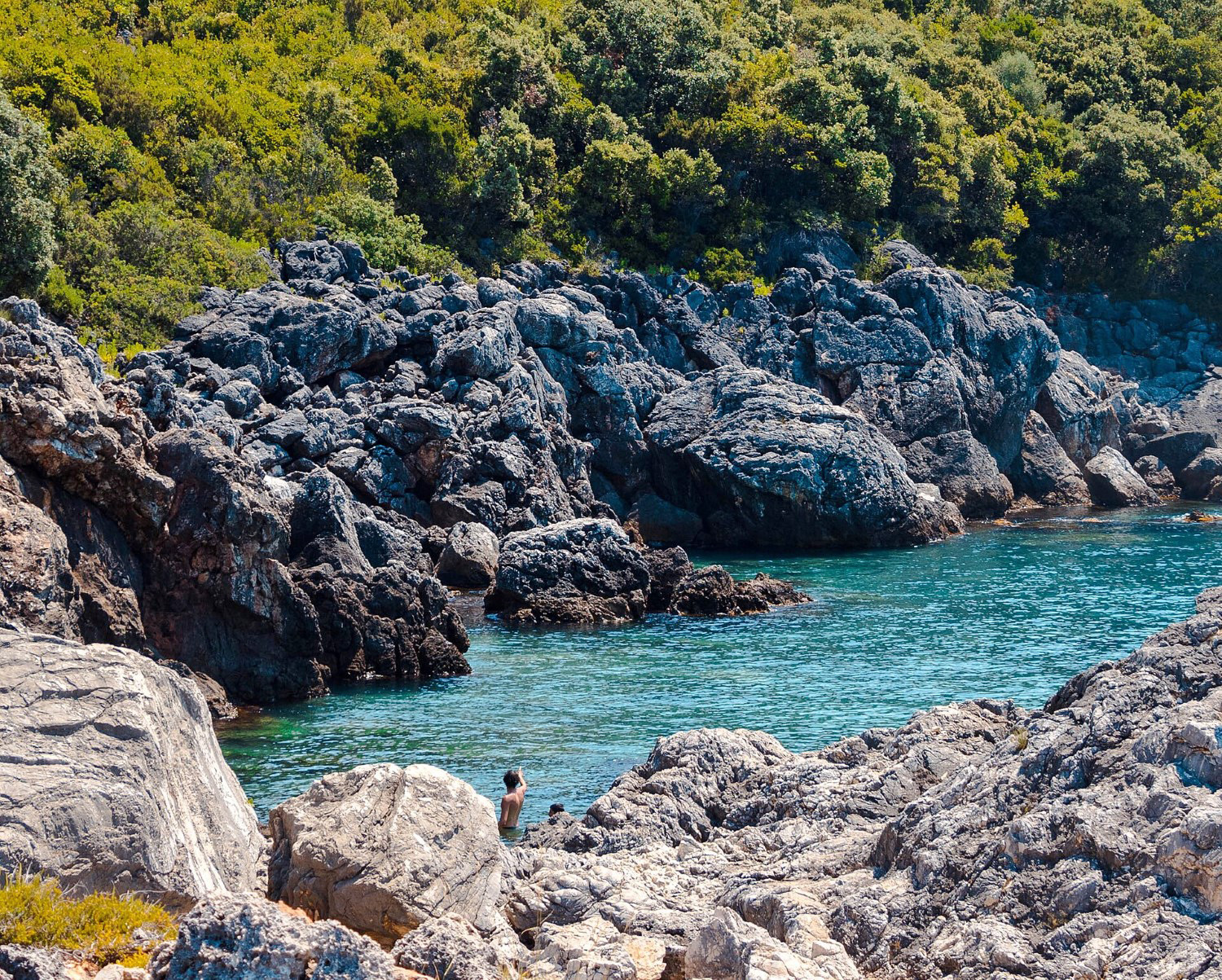 Aquarium Bay Albania — crystal-clear turquoise water in a wild volcanic cove on the Ionian coast