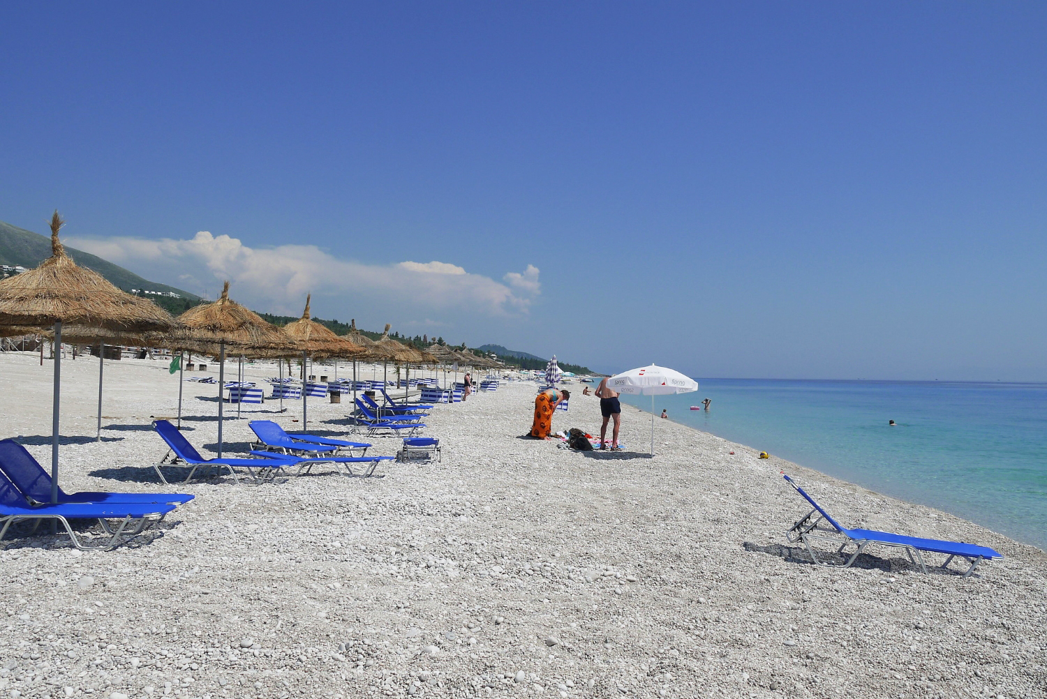 Dhërmi Beach Albania — view of the beach strip with beach clubs and Ceraunian Mountains backdrop